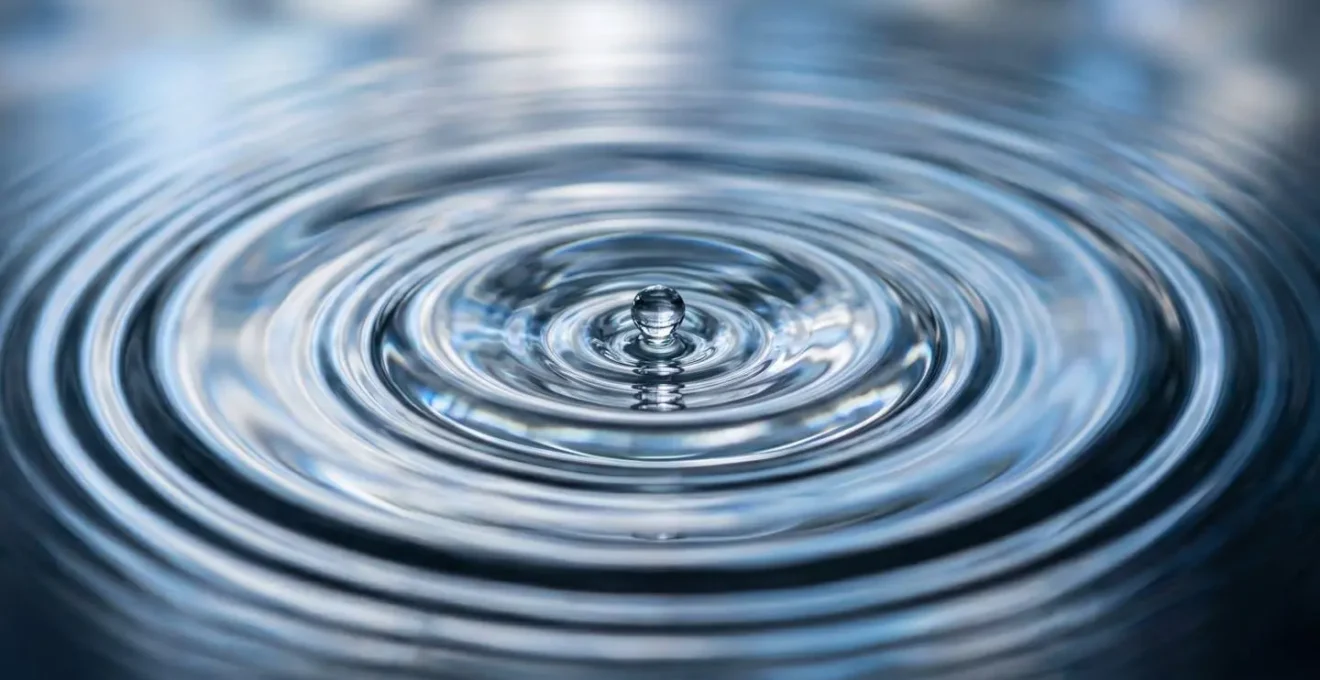 Macro close-up of water droplets creating ripple effects symbolizing compound growth