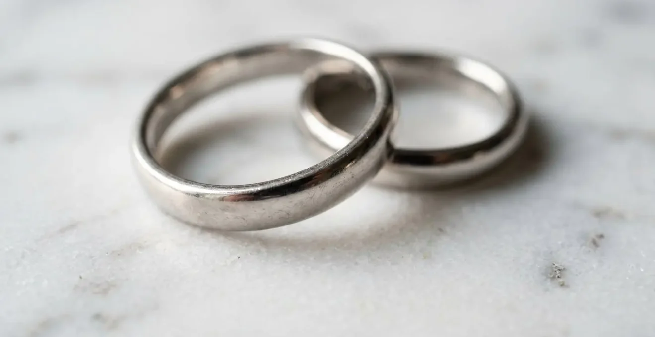 Two elegant minimal wedding rings resting on clean architectural surface symbolizing financial partnership